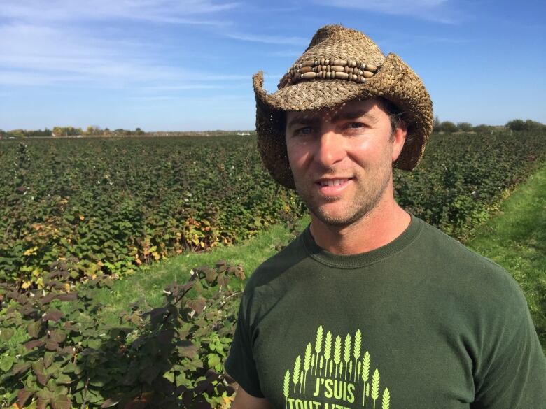 A man wearing a straw hat standing in a field.