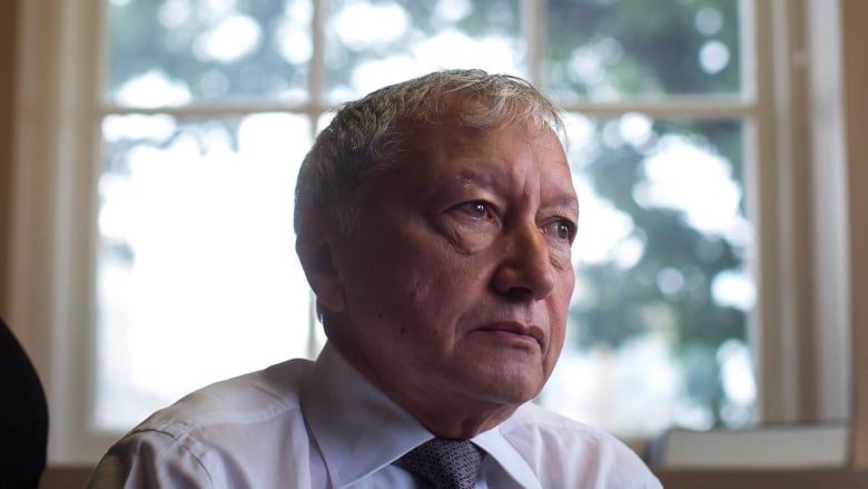 A man sits in front of a window