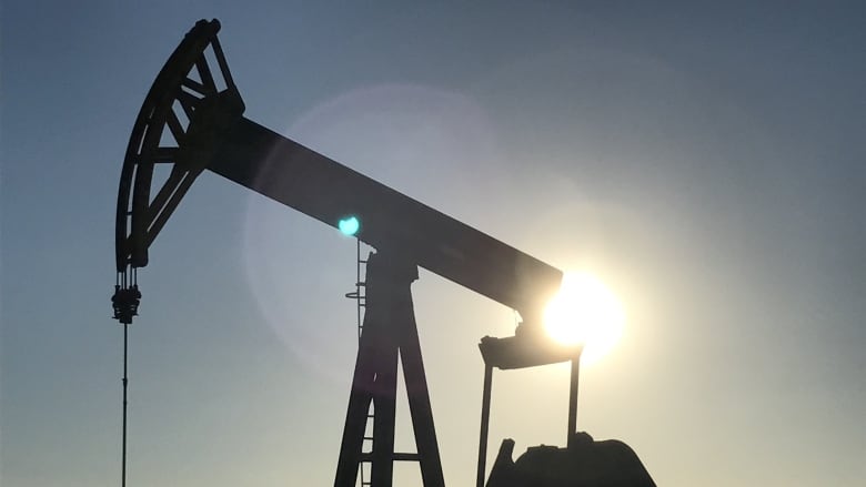 An image shows a petroleum pumpjack against a dusky sky in close up.