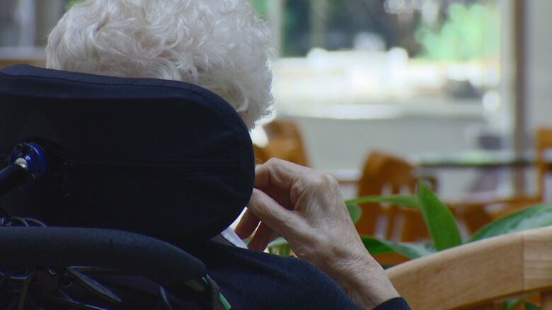 A  read view of a woman sitting in a wheelchair looking out a window.