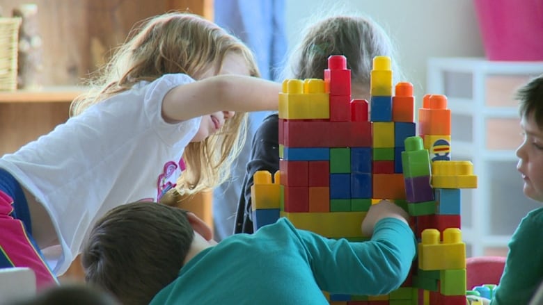 Three preschool kids play with colourful blocks.