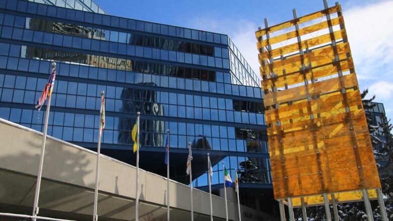 a photo of a glass building with different flags in front of it