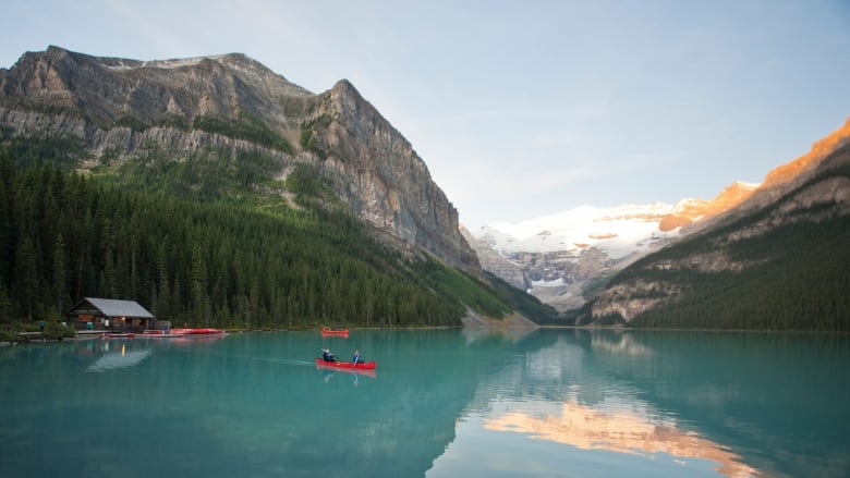 People canoeing across the turquoise waters of Lake Louise.