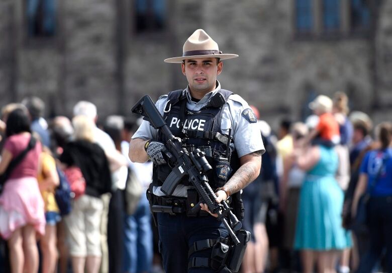 An RCMP officer carries a rifle.