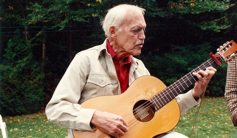 An old man holding a guitar