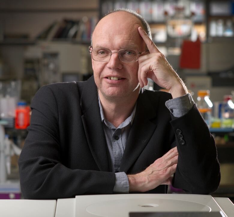 Professor Keith Warriner sits with his hand against his head while smiling to camera