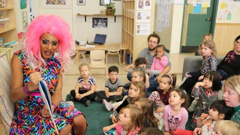 a drag queen reading a book to children