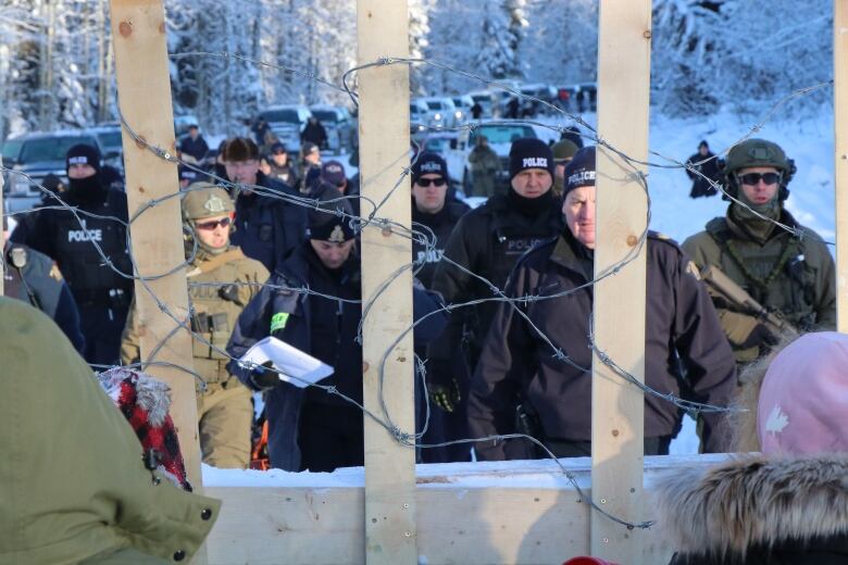 Police and activists face off through a barbed-wire barricaded.