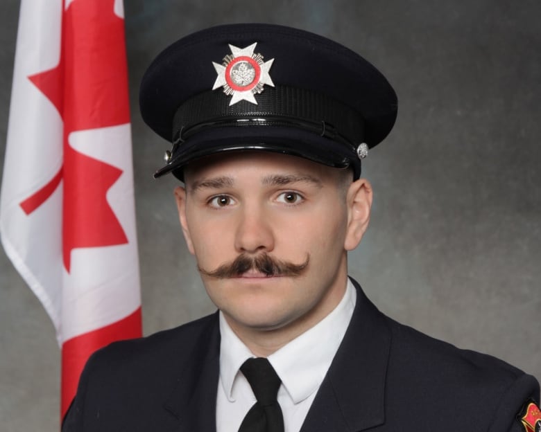 A young man is pictured in uniform with a fire hat and moustache. 