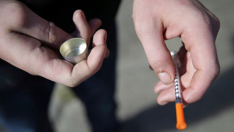 a fentanyl user holds a needle near Kensington and Cambria in Philadelphia