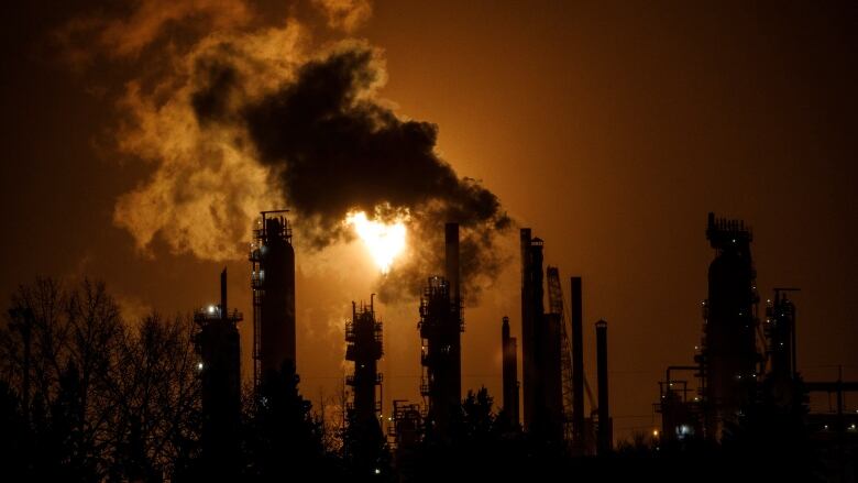 A flare stack from an oil refinery with an orange hue. 