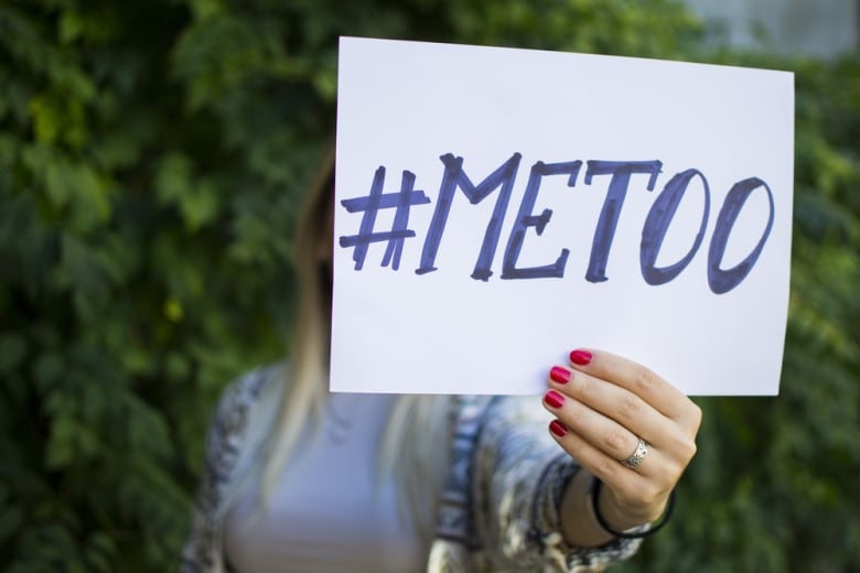 A woman's hand holds a #MeToo sign.