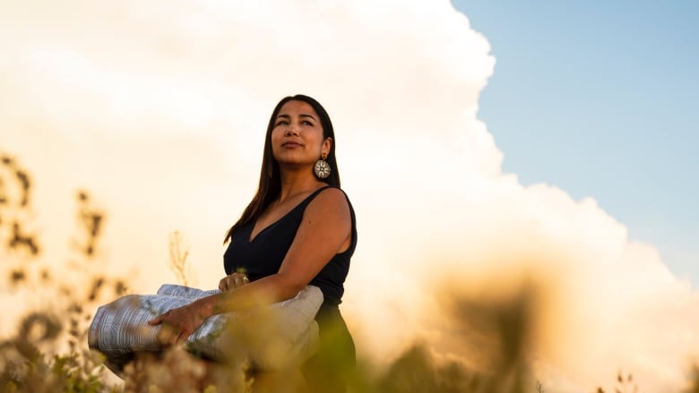 A woman standing in a field is pictured.