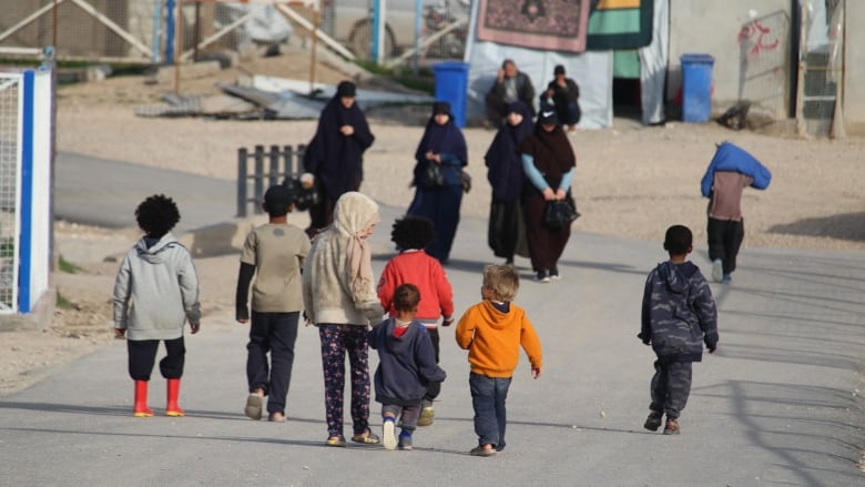 women and children seen from behind walking along an rural looking road