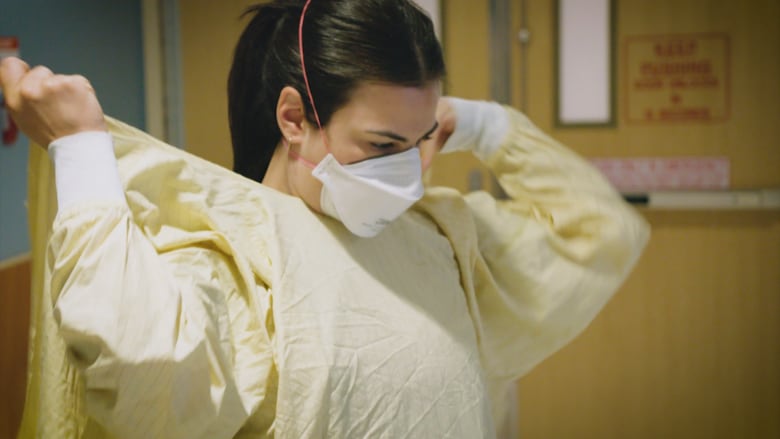 A masked nurse puts on a mask.