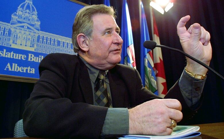 An older Ralph Klein takes questions at the legislature in a file photo. He is dressed in a suit and tie.