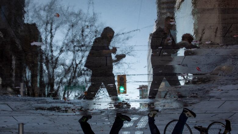 People are pictured reflected in a pool of water.