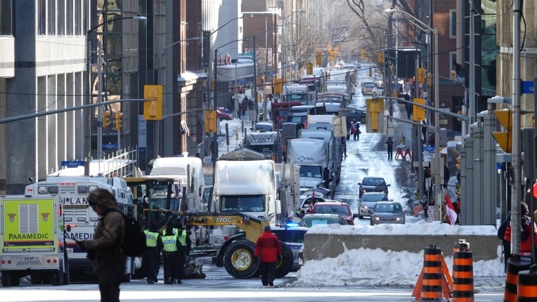 A line of parked trucks for blocks of a downtown city street in winter.