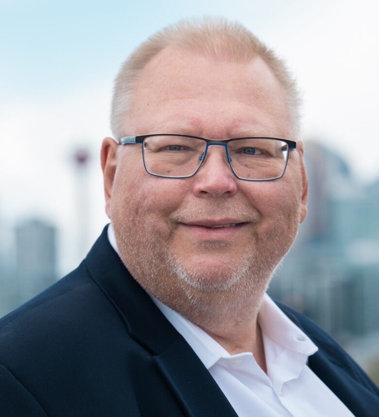 Headshot of a man wearing a shirt and suit jacket