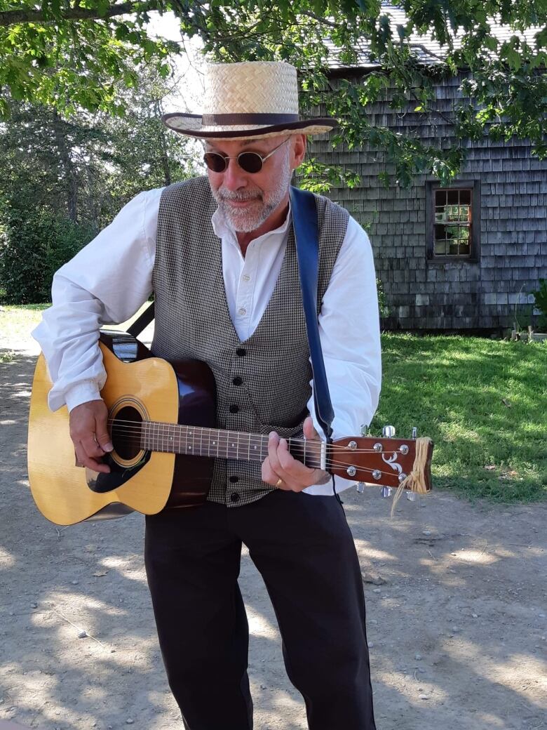 Man plays guitar in old timey outfit