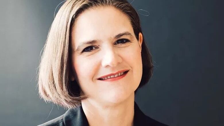 A portrait of a woman in front of a grey background.