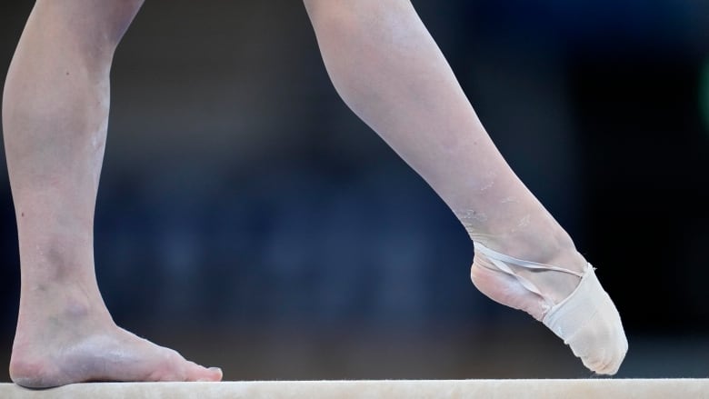 A gymnasts legs are seen on a balance beam.