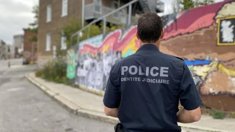 A police officer stands in front of Black Lives Matter mural in Quebec City. 