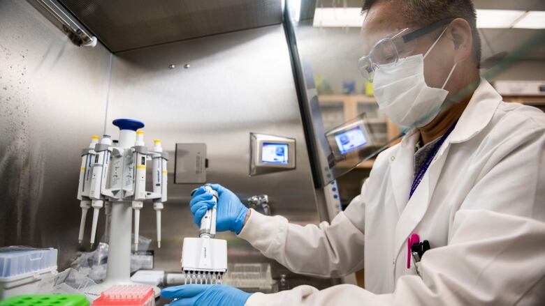 A researcher in a lab coat operates equipment.