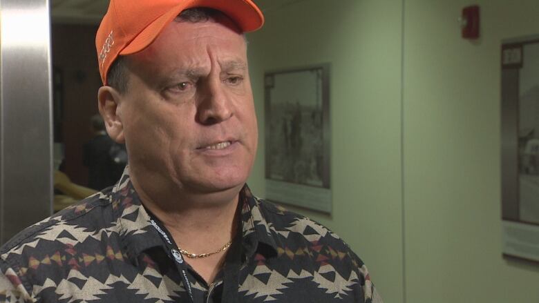 A middle-aged man wearing an orange baseball hat.