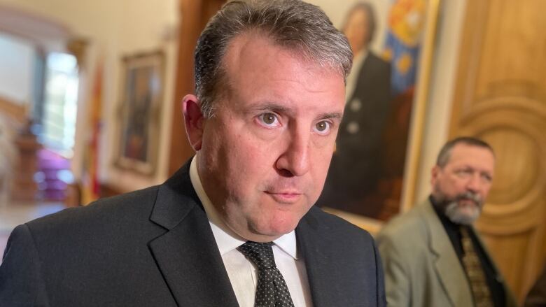 A man speaks to reporters inside the New Brunswick legislature.