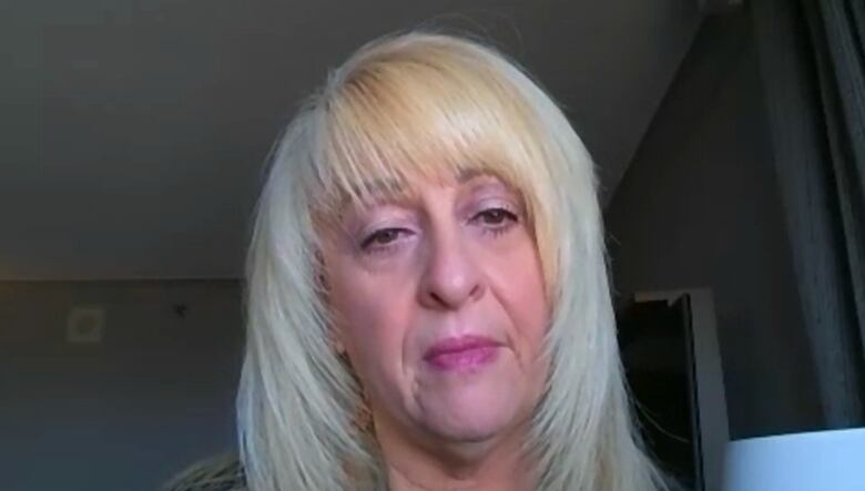 A woman with blonde hair wearing a black shirt sitting in a hotel room