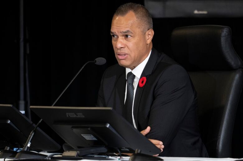 A man in a suit speaks into a microphone.