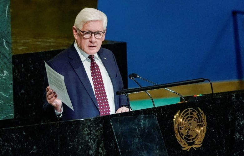 A man wearing glasses speaks at a podium.