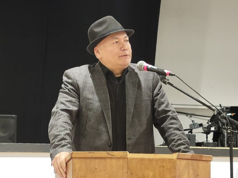 Chief Larson Anderson stands at a podium wearing a grey brimmed hat and jacket.