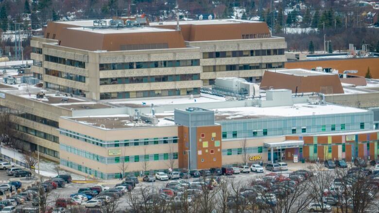 From above, a hospital building and parking lot on a snowy day.