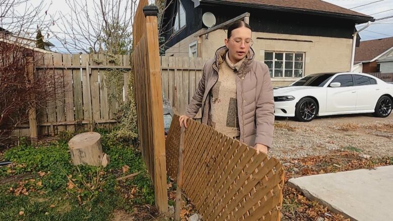 A woman holds a small temporary fence. 