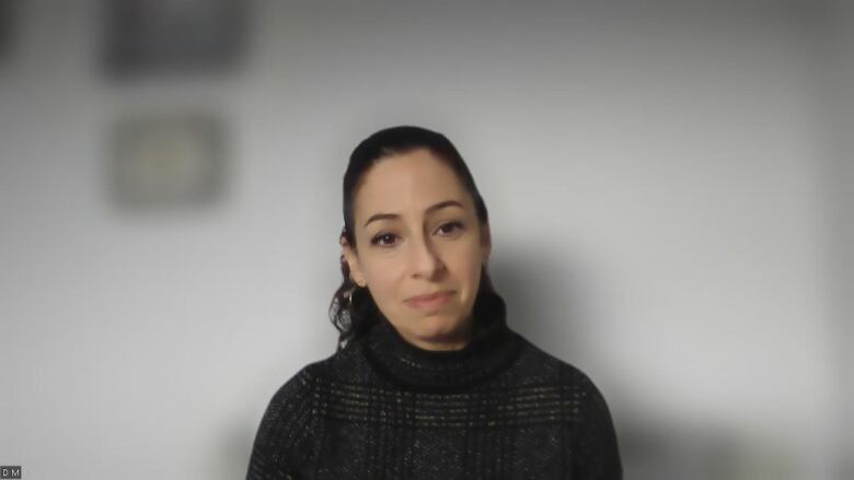 A woman sits infront of a white wall.