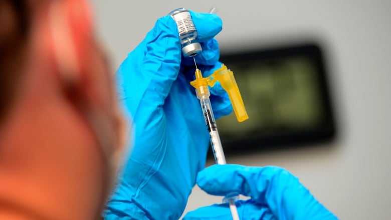 A health-care worker prepares a dose of Pfizer's bivalent COVID-19 vaccine.