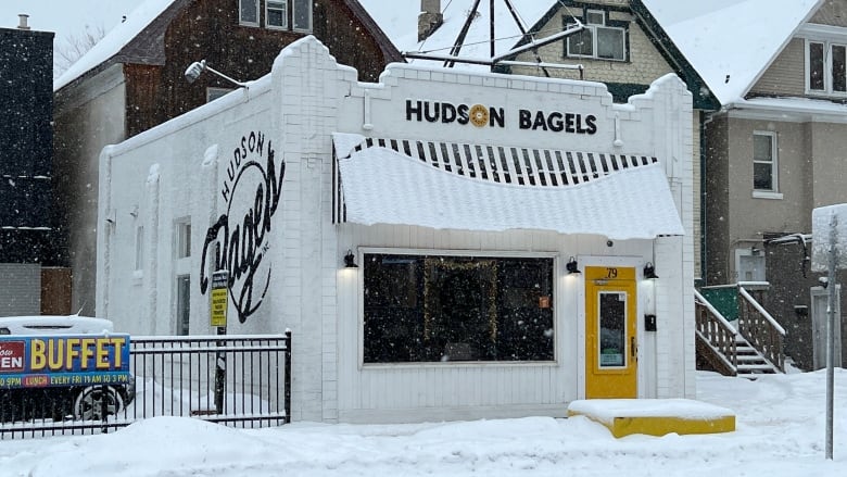 A black-and-white store with a yellow door in the winter.