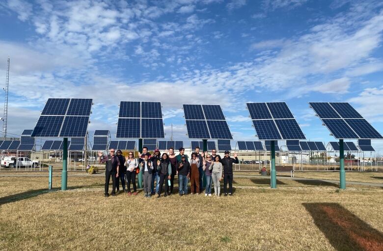 People congregate in front of a solar power array in Alberta on a sunny day.