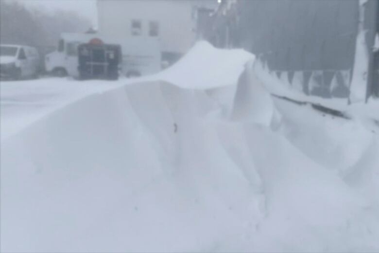 A high snow drift covers a vehicle.