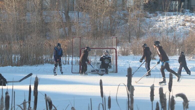 A group of people playing hockey on a storm pond.