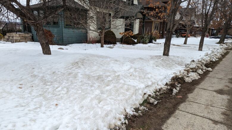 A snowy front lawn with some grass exposed.