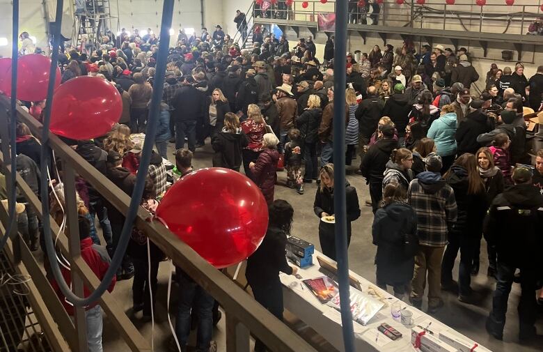 Many people stand in a hall.