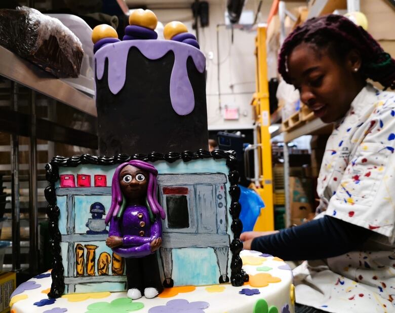 Baker Rochelle Williams smiles as she decorates a cake with her signature character.