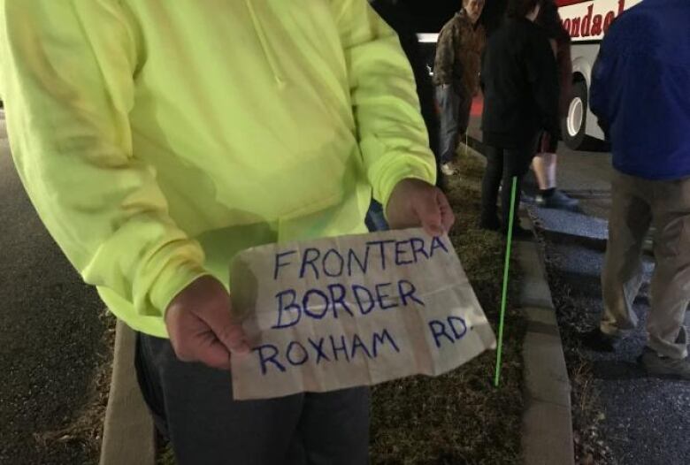 Hands holding a sign that reads 