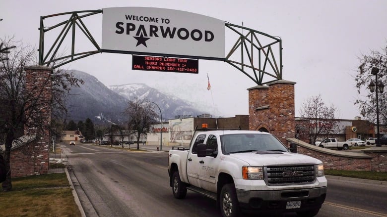 A truck passes under a sign that reads, 'Welcome to Sparwood.'