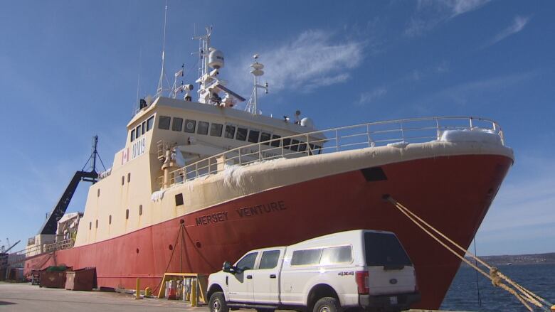 A red fishing vessel tied up at a dock.