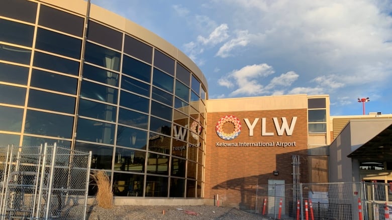 The front facade of the Kelowna International Airport has curved classed windows plus a colourful logo and 