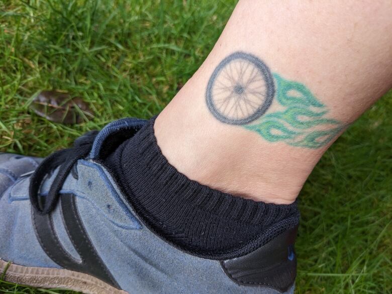 Am ankle tattoo of a bike tire with blue flames.